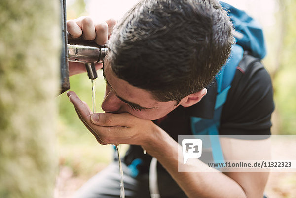 Hiker drinking water from a well