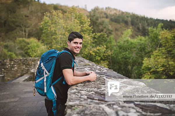 Portrait of a smiling hiker leaning on stone wall