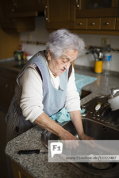 Seniorin beim Geschirrspülen in der Küche
