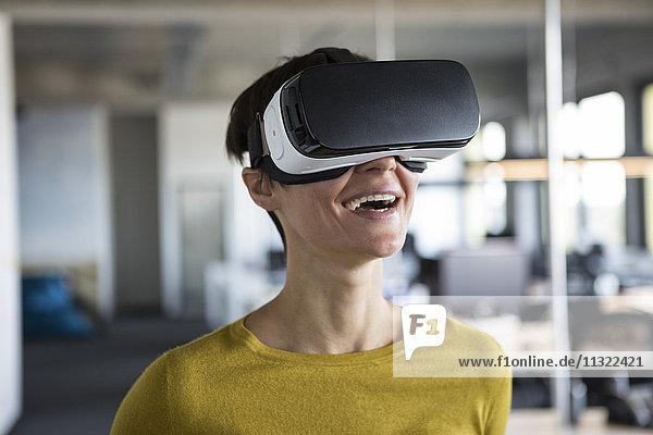 Glückliche Frau im Büro mit Virtual-Reality-Brille