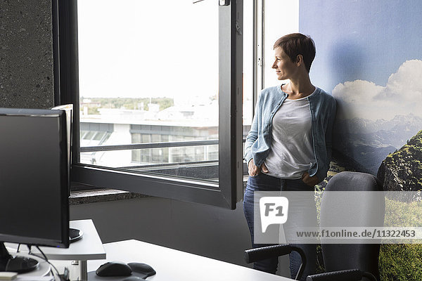 Geschäftsfrau im Büro mit Blick aus dem Fenster
