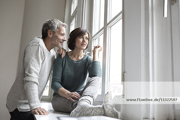 Erwachsenes Paar  das aus dem Fenster schaut