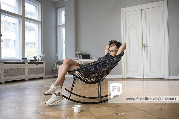 Junge Frau entspannt auf Schaukelstuhl zu Hause