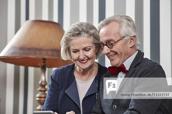 Glückliches Seniorenpaar mit Smartphone zu Hause
