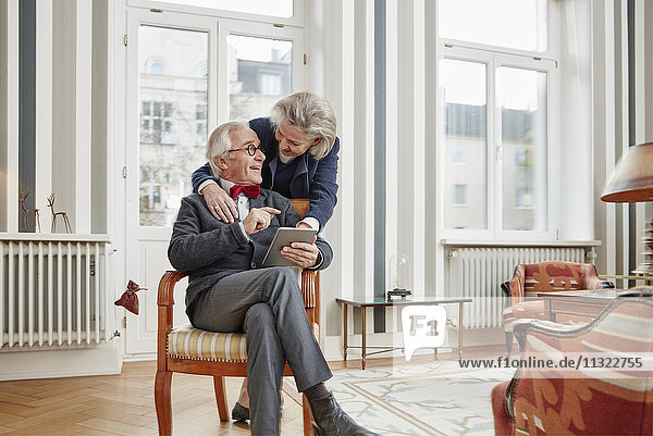 Glückliches Seniorenpaar mit Tablette zu Hause