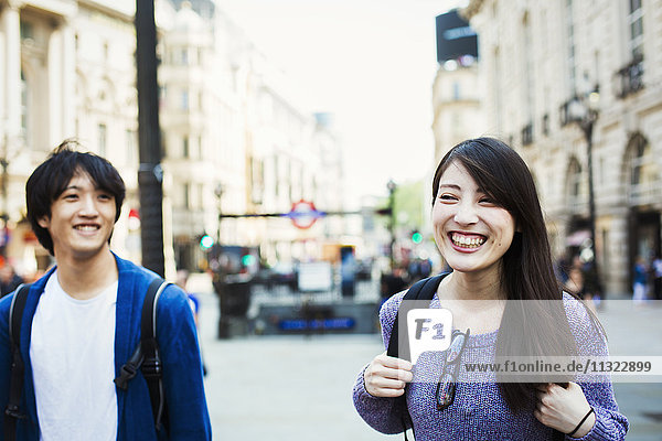 Ein junger Japaner und eine junge Japanerin genießen einen Tag in London bei einem Spaziergang in der Nähe des Piccadilly Circus.