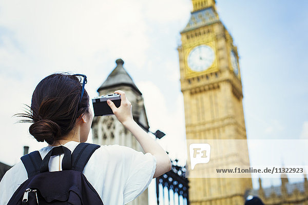 Junge Japanerin genießt einen Tag in London und macht ein Foto von Big Ben.