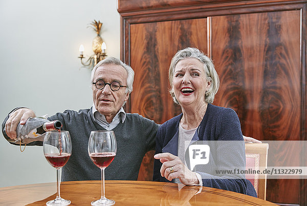 Fröhliches Seniorenpaar trinkt Rotwein