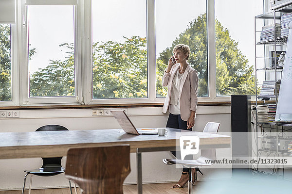 Businesswoman talking on cell phone in modern conference room