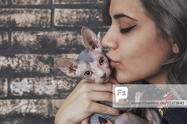 Young woman kissing Sphynx cat