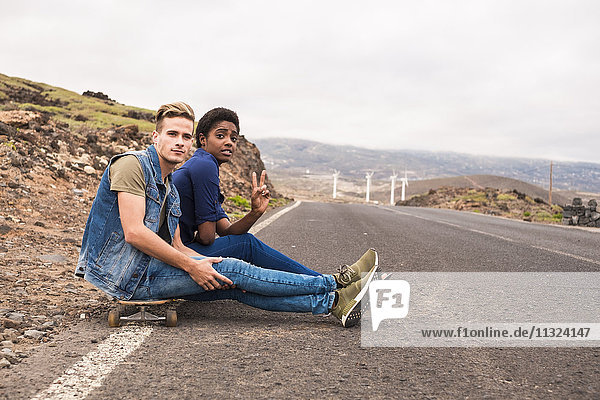 Spain  Tenerife  two friends with skateboard sitting at roadside