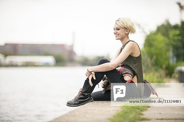 Lächelnde blonde Frau entspannt am Flussufer