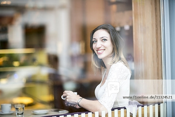 Junge Frau sitzt im Café und trinkt Kaffee.