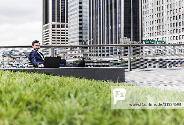 USA  New York  Manager in Manhattan sitting outdoor  using laptop
