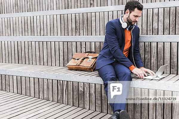 USA  New York City  Businessman sitting on stairs using digital tablet