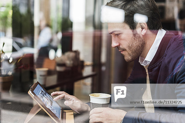 USA  New York City  Geschäftsmann sitzend im Coffee Shop  mit digitalem Tablett