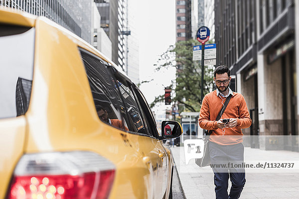 USA  New York City  Businessman approaching cab  using smart phone