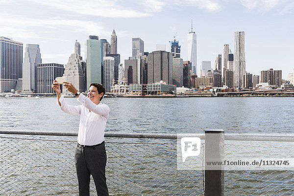 USA  Brooklyn  glückliche Geschäftsfrau vor der Skyline von Manhattan