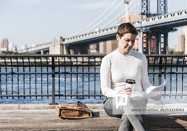 USA  Brooklyn  Geschäftsfrau auf der Bank sitzend  Dokumente lesend