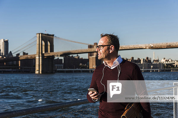 USA  Brooklyn  Geschäftsmann mit Smartphone vor der Brooklyn Bridge