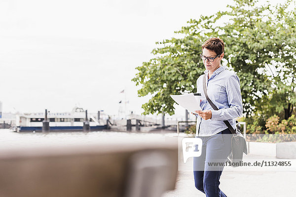 USA  New York City  Geschäftsfrau beim Spaziergang am East River Lesedokument