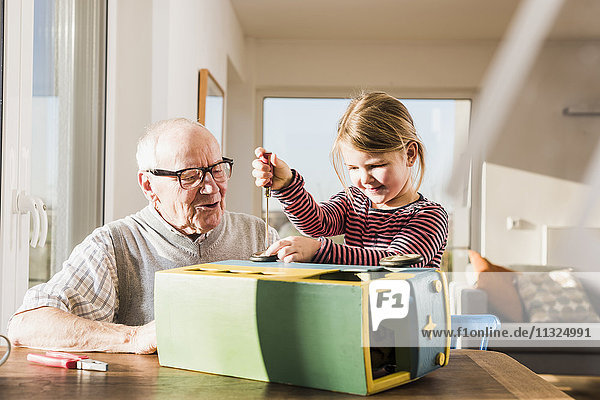 Großvater und Enkelin beim Zusammenbau des Spielzeugbusses