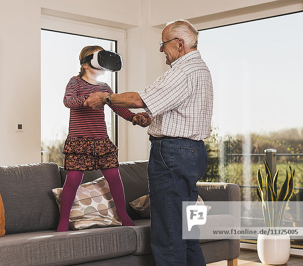 Grandfather holding granddaughter  using VR glasses