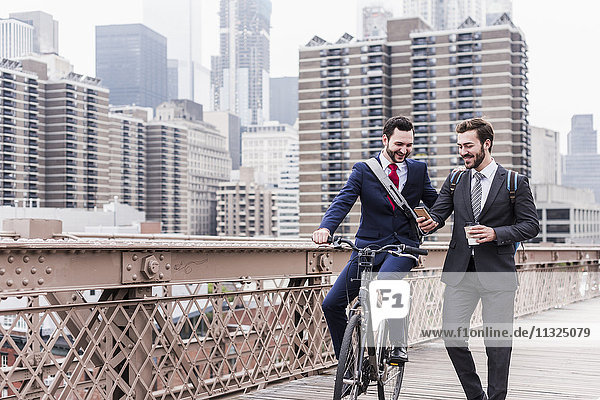 USA  New York City  zwei lächelnde Geschäftsleute auf der Brooklyn Bridge