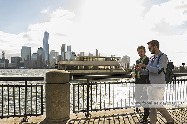 USA  two businessmen walking at New Jersey waterfront with view to Manhattan