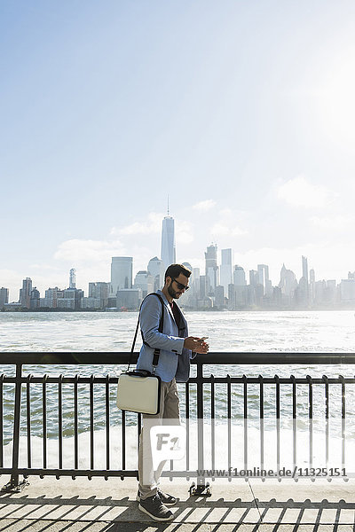 USA  Mann mit Handy an der New Jersey Waterfront mit Blick auf Manhattan
