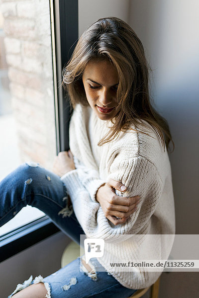 Junge Frau am Fenster sitzend