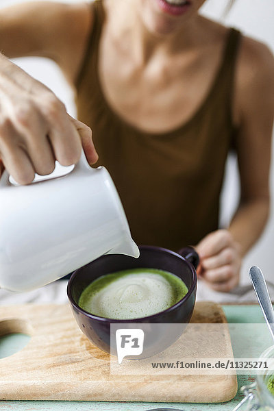 Woman preparing matcha latte at home