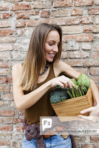 Lächelnde Frau mit Bix und frischem Gemüse