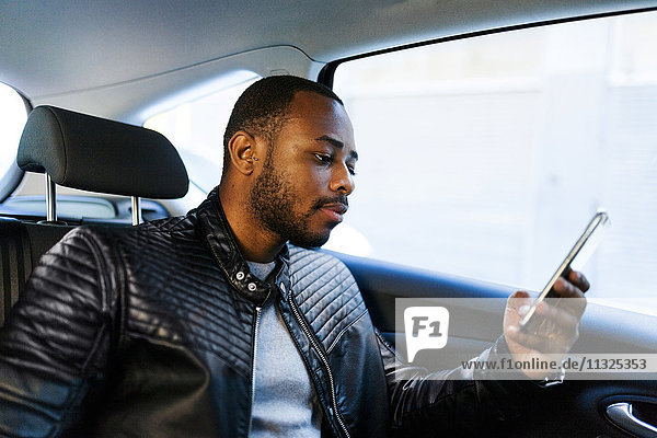 Young man using smartphone in taxi