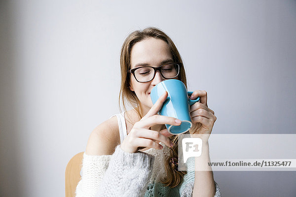 Young woman at home drinking cup of coffee