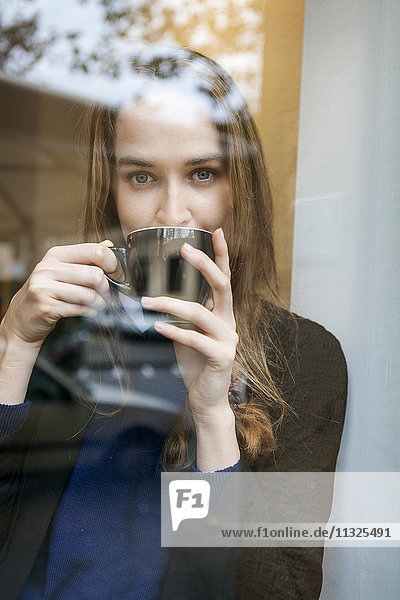 Portrait of young woman in coffee shop drinking coffee