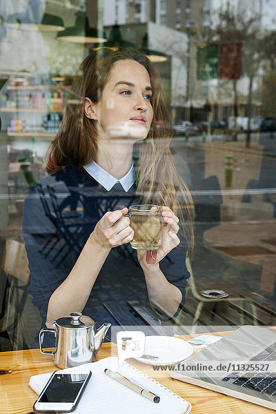 Junge Frau mit Laptop und Tasse Tee im Café