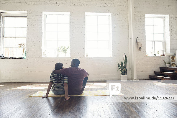 Young couple sitting on carpet in a loft