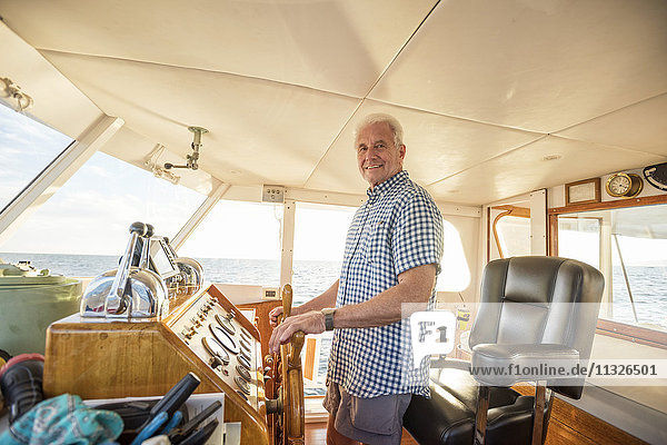 Zuversichtlicher Senior steuert ein Boot
