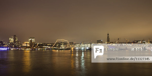 Deutschland  Hamburg  Blick auf die beleuchtete Stadt mit der Elbe im Vordergrund