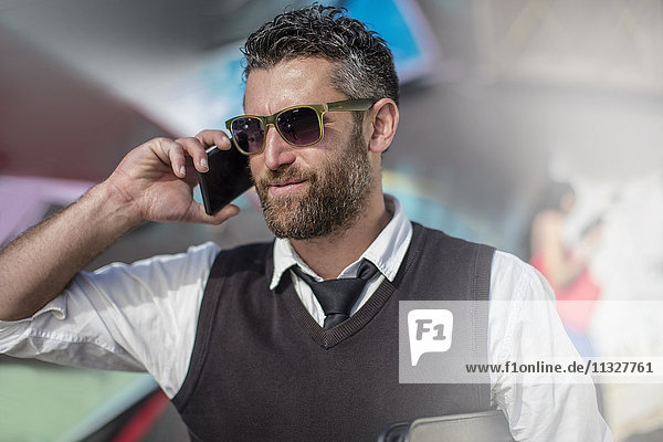 Smiling man wearing sunglasses talking on cell phone