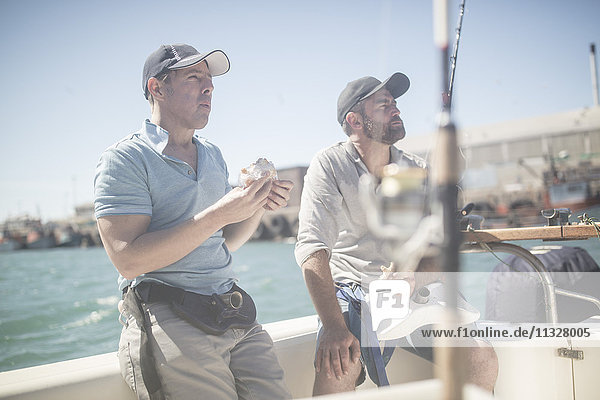 Zwei Männer bei der Mittagspause auf dem Boot mit Angelruten