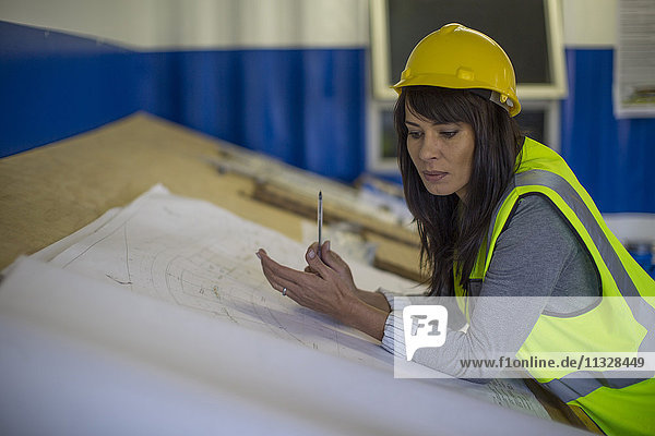 Female construction engineer in site office working with blueprint