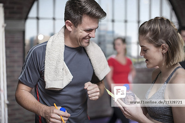Junger Mann und Frau bei einer Pause im Fitnessraum