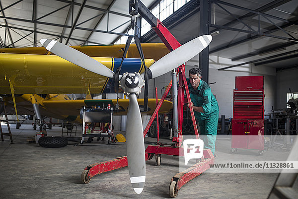 Mechanic in hangar pushing propellor of light aircraft