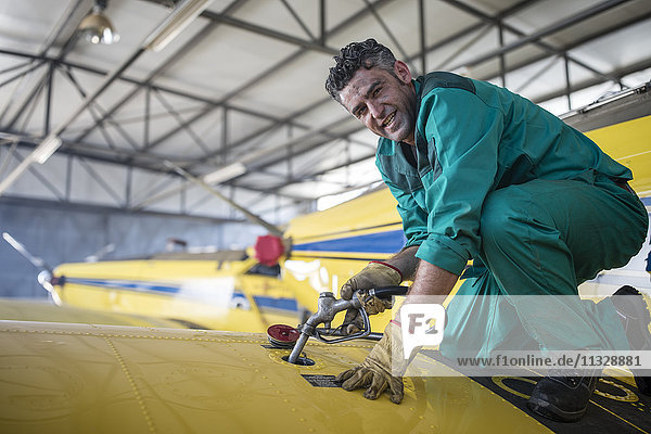 Mechanic in hangar refilling tank of light aircraft
