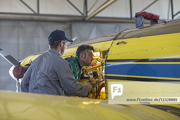 Mechanics in hangar repairing light aircraft