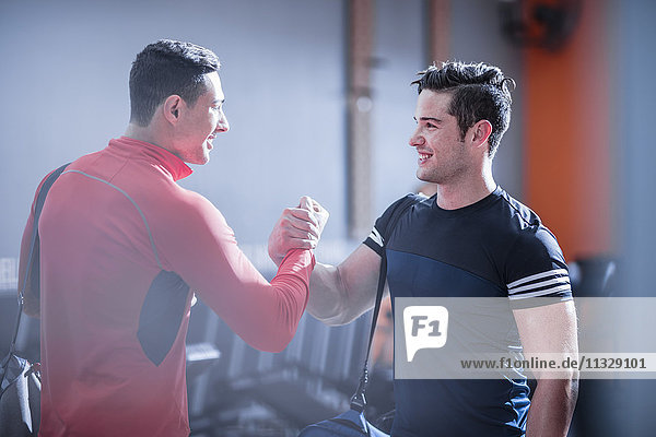 Zwei junge Männer beim Händeschütteln im Fitnessstudio