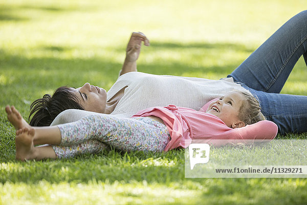 Mother and daughter lying in grass