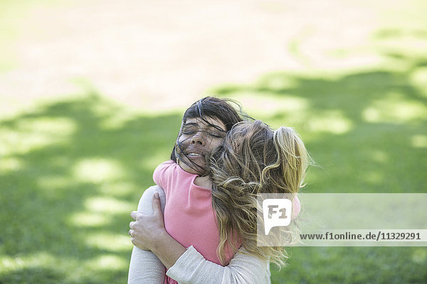 Mutter umarmt Tochter im Garten